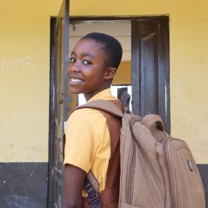 girl with backpack entering school classroom