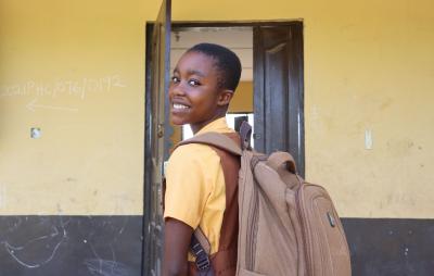 girl with backpack entering school classroom