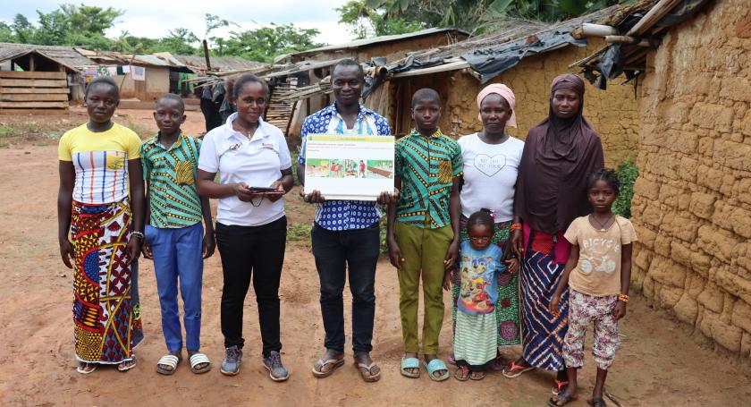 community facilitator poses with a farming family