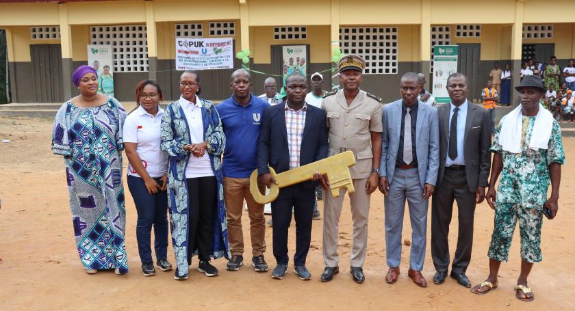 partners and stakeholders posing in front of the school building with the school key
