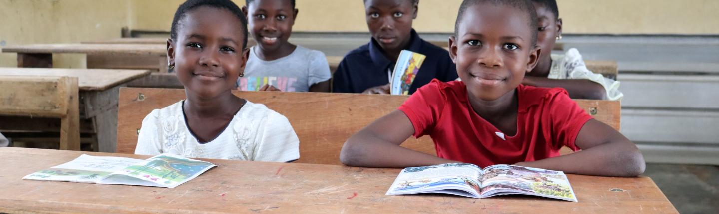 a girl and a boy sitting at a school desk with books